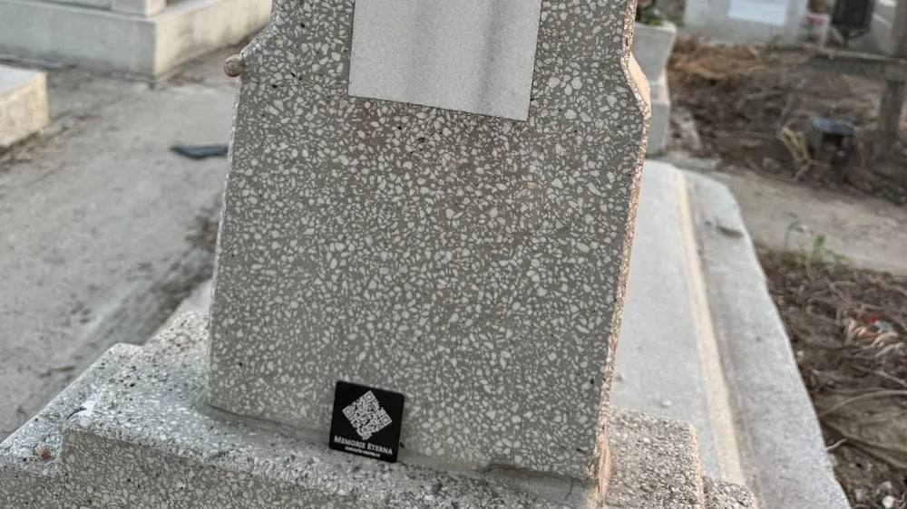 Plăcuța Memorie Eternă montată la baza crucii, în amurg